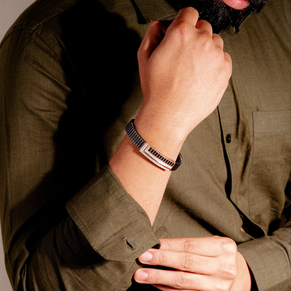 Person wearing a green shirt and beige pants with a watch on a neutral background
