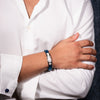 Person wearing a white shirt with rolled-up sleeves and a blue wristband.