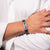 Person wearing a bracelet with text on a white shirt background
