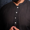 Man wearing a black kurta against a dark background