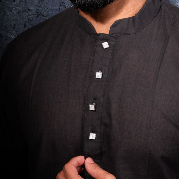 Man wearing a black kurta against a dark background