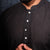 Man wearing a black kurta against a dark background