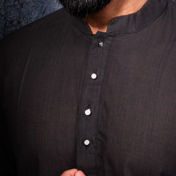 Man wearing a black kurta with a close-up of the shirt design.